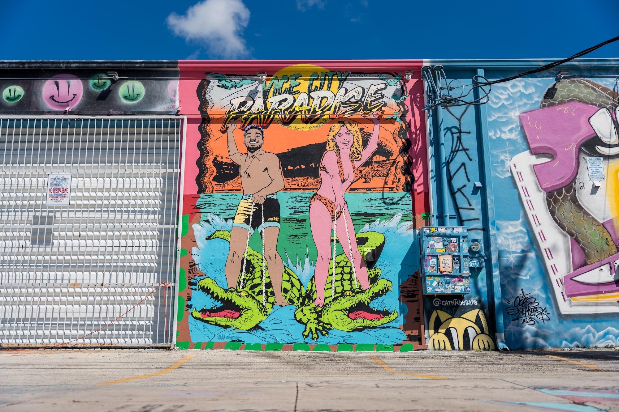 A Grand Theft Auto VI mural in Miami's Wynwood neighborhood, showing a Vice City beach scene with alligators under a Paradise sign